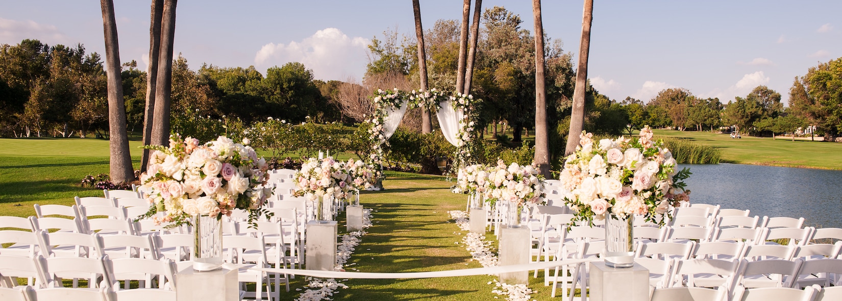Outdoor wedding ceremony at Los Coyotes with white chairs facing a floral arch