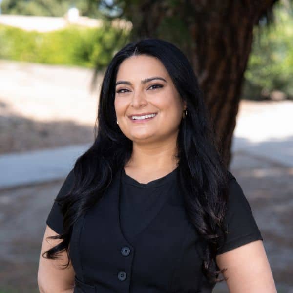 Smiling woman with long dark hair in a black top, outdoors