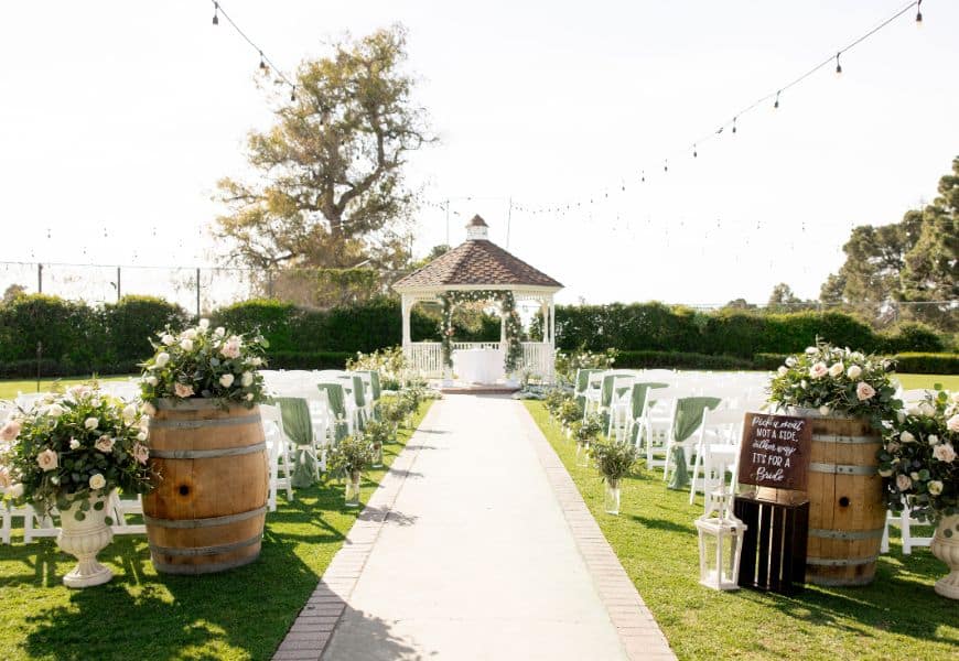Ceremony aisle with wine barrels, florals and string lights at El Dorado