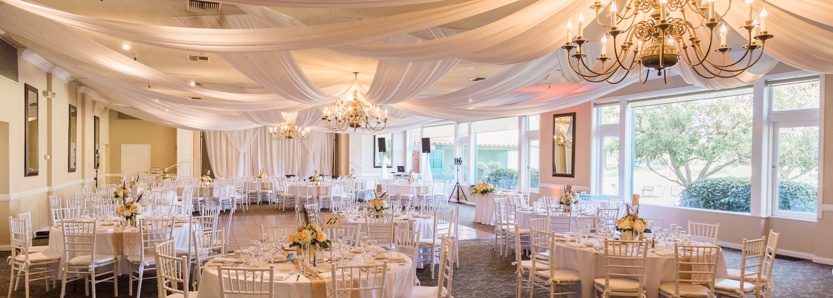 Ballroom set with round tables, ceiling draping and chandeliers