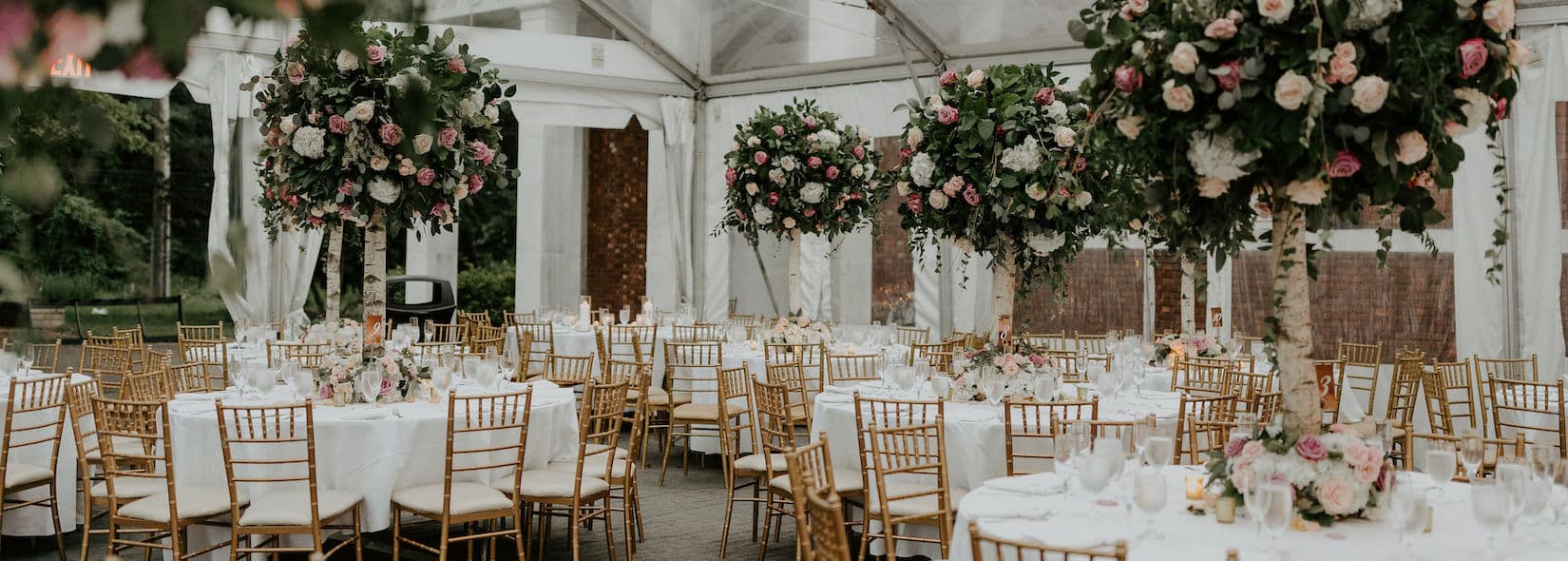 Tented reception with tall floral centerpieces, gold chiavari chairs and white linens