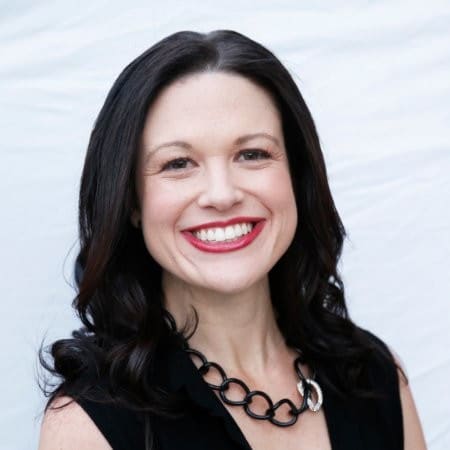 Jackie Lowe, smiling in a black top and chain-link necklace