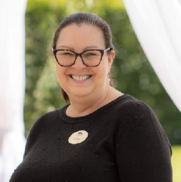 Patty, smiling in glasses and a black sweater with a name badge