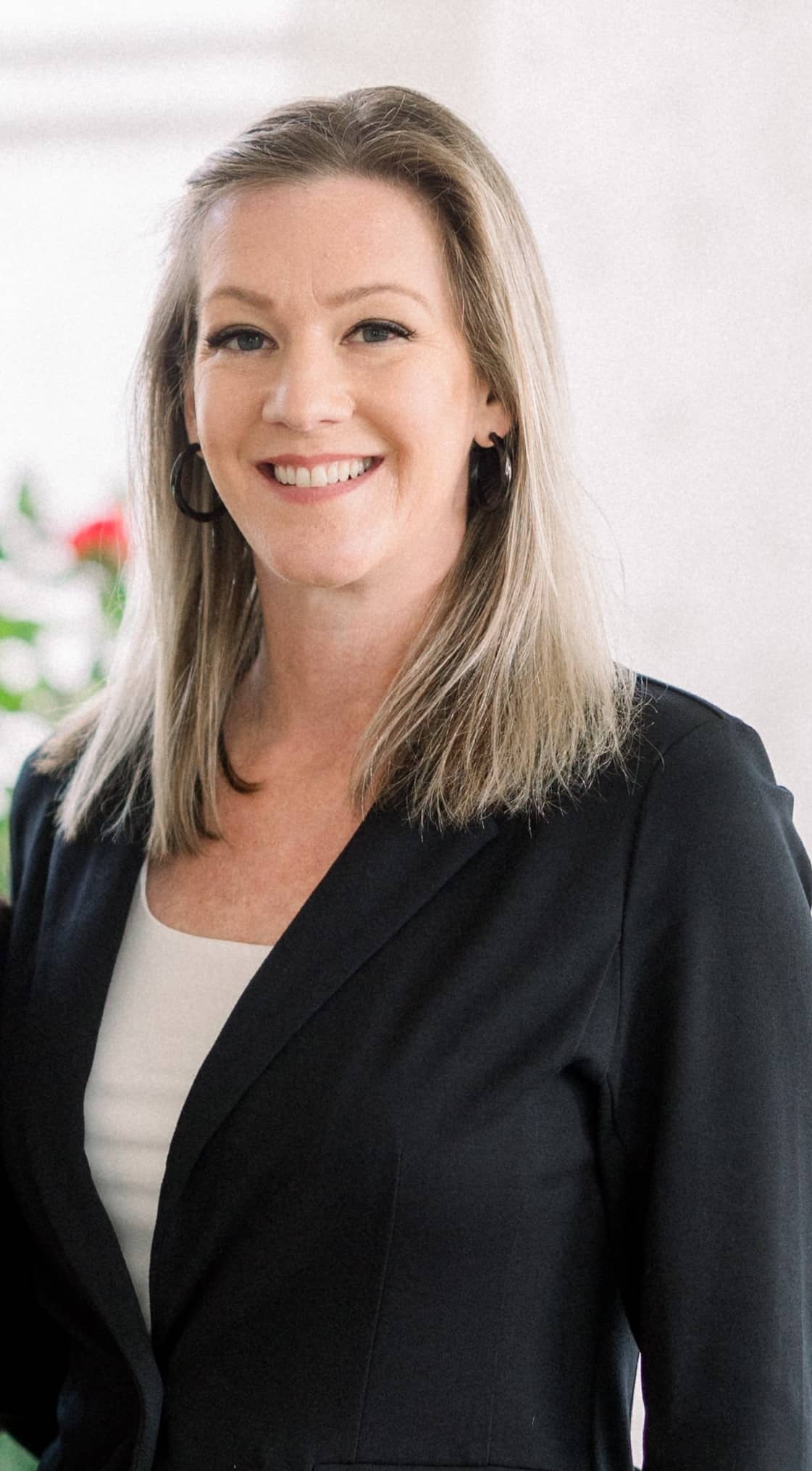 Stacy, smiling in a black blazer over a cream top